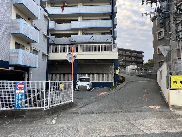 名子側の入口。車止めと、防犯カメラ稼働中の表示があります。