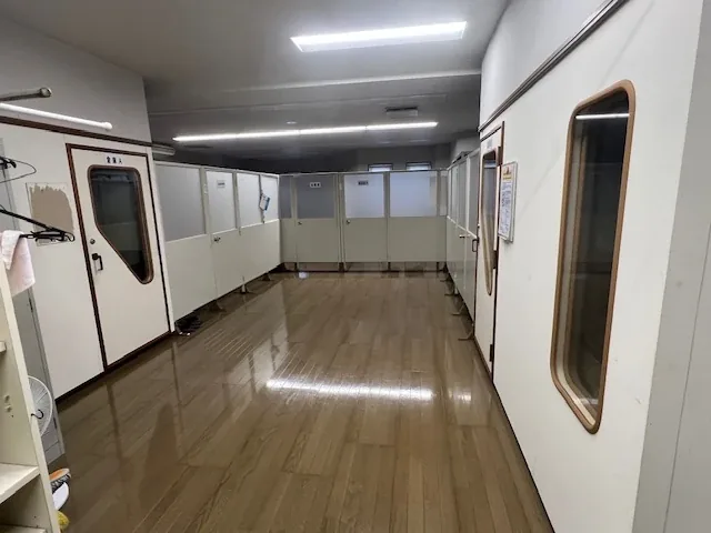 コミュニティルーム。白い間仕切りで区切られ、丸窓の付いた扉が並んでいます。