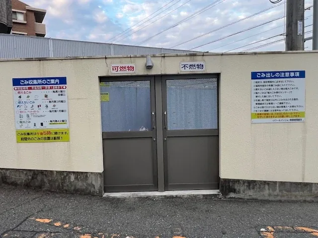 ごみ収集所を正面から見たところ。可燃物と不燃物の扉が分かれ、両脇に出し方の案内が掲示されています。