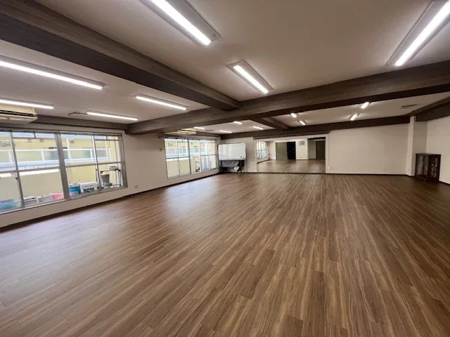 リフォームされたばかりの集会所。木目の床と白い壁の広い一室で、窓から光が入っています。