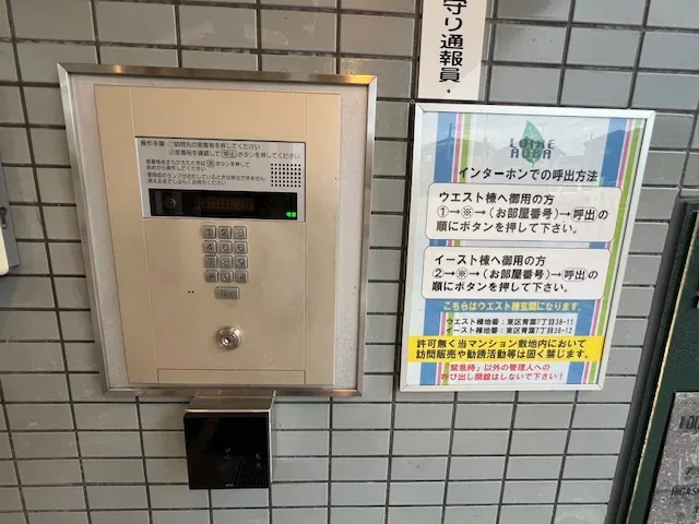 玄関のインターホン。隣に、ウエスト棟・イースト棟それぞれの呼出の手順を書いた案内が掲示されています。