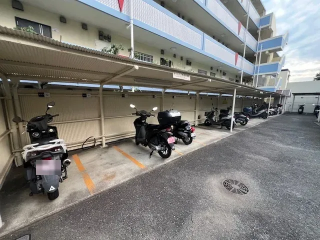 屋根付きのバイク駐輪場。区画線に沿って原付やバイクが並んでいます。