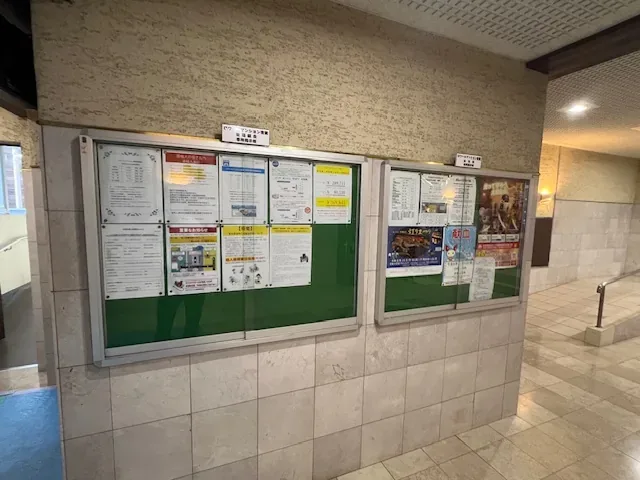 ウエスト棟の掲示板。ガラスの扉が付いた2面の掲示板に、お知らせが貼られています。